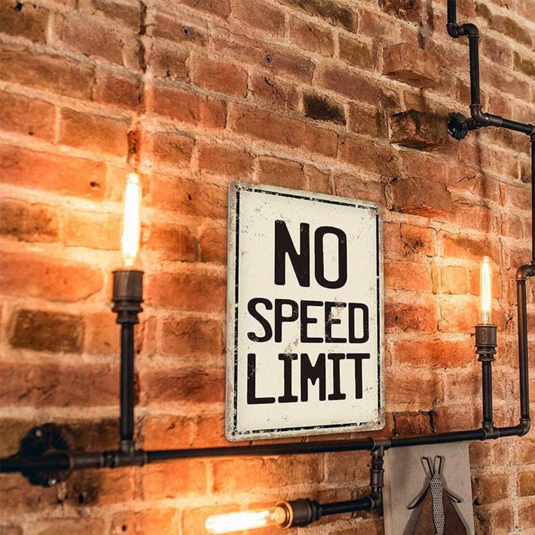 Weißes Metallschild mit schwarzer Aufschrift No Speed Limit auf einer Ziegelwand mit Lichter
